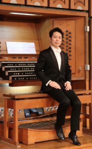 Johannes Il-Hwan Yoo sitzt auf der Orgelbank mit dem Rücken zur Orgel